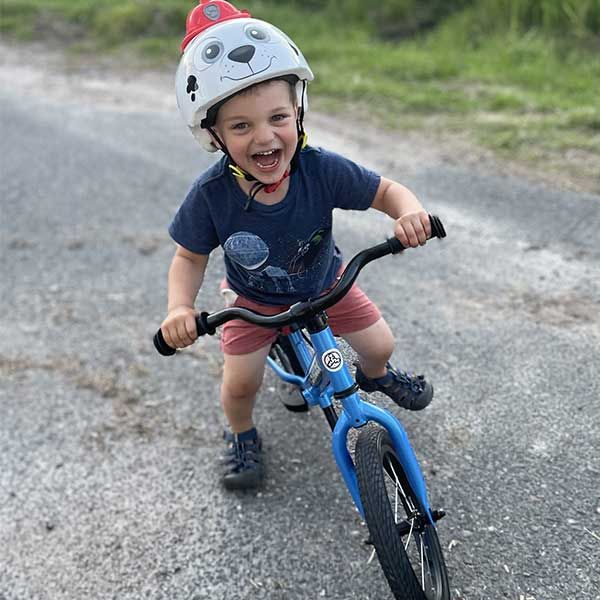 Laughing on a blue Strider 14x balance bike