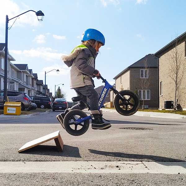 Jumping a blue Strider bike on a homemade ramp