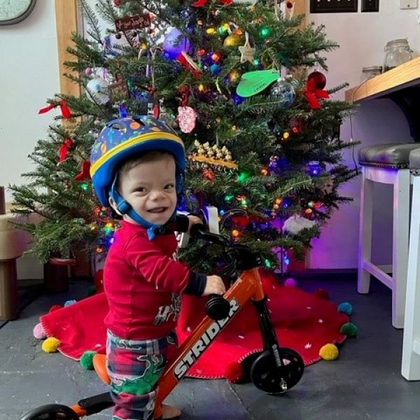 Lincoln Drake smiles as he sits on his adaptive 12" Strider Sport for the first time