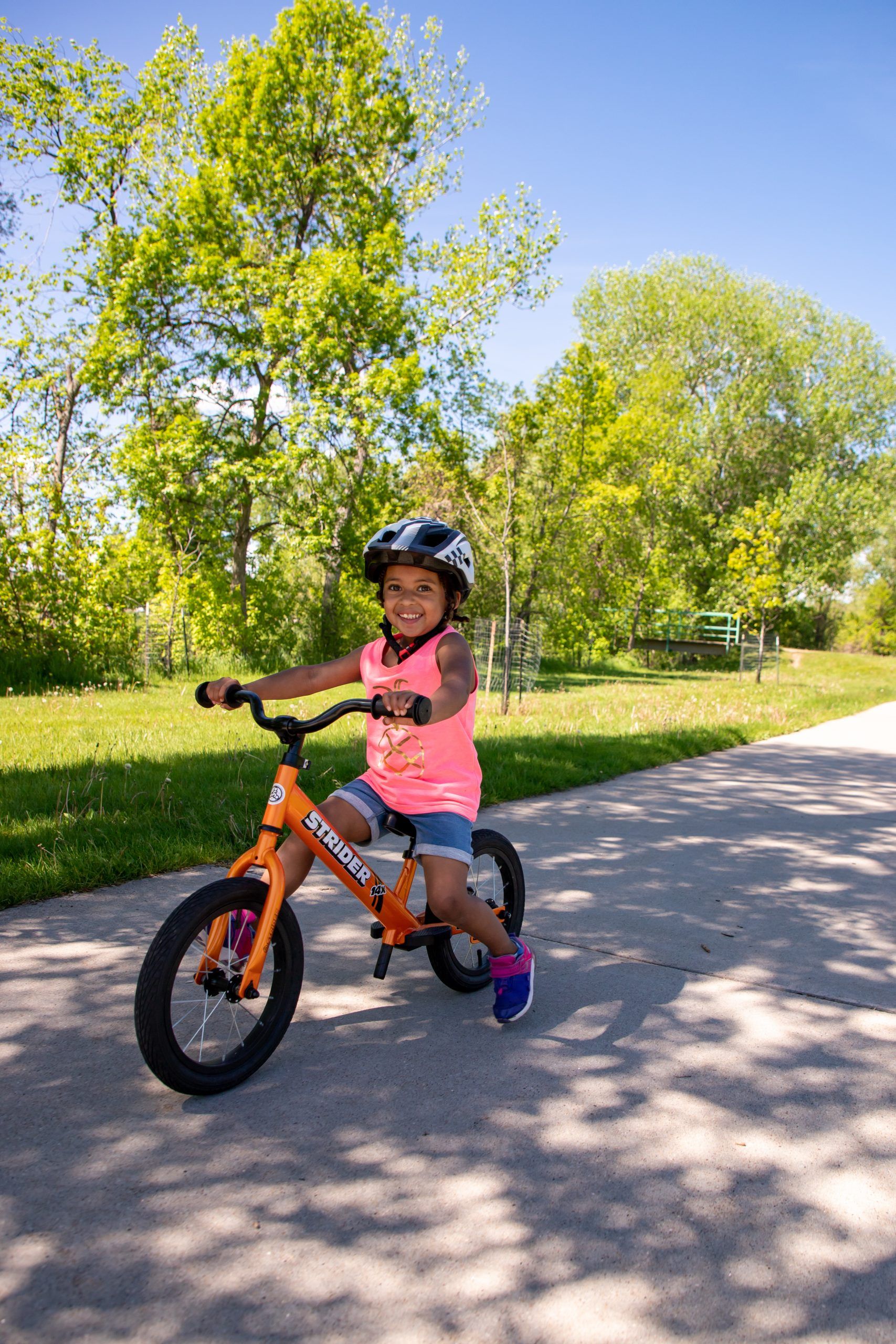 A girl rides a Tangerine Strider 14x Sport